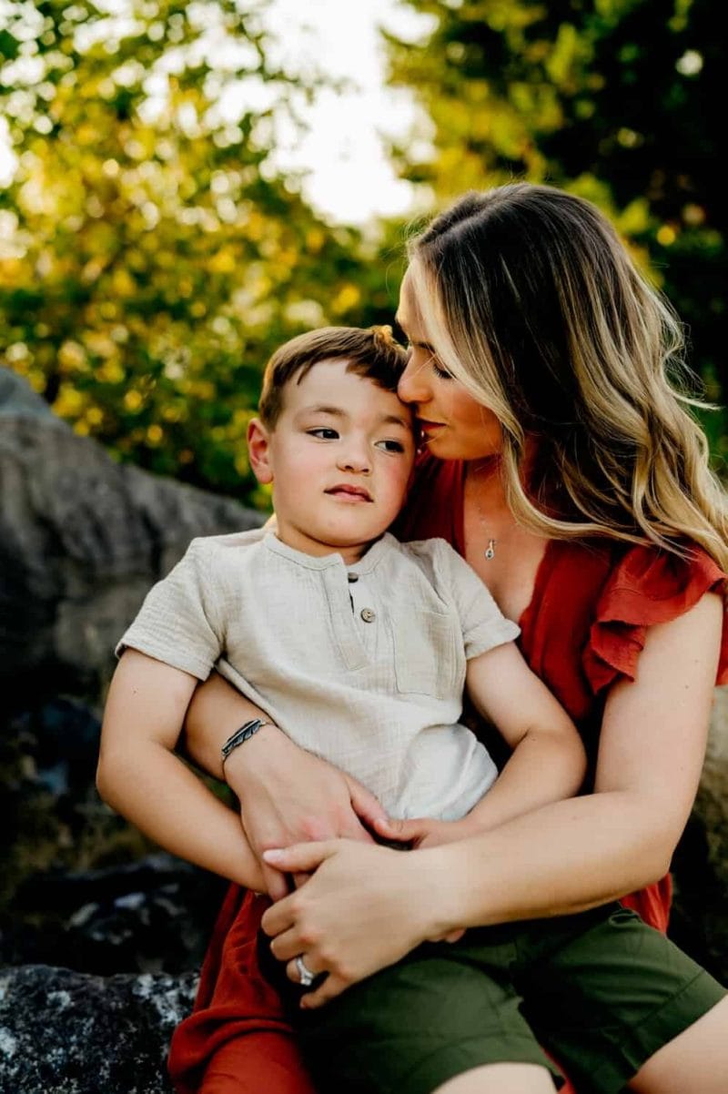 mom holding son while being photographed by a family photographer