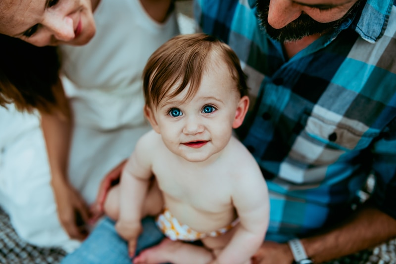 Family Photographer, Baby is happy sitting with mom and dad