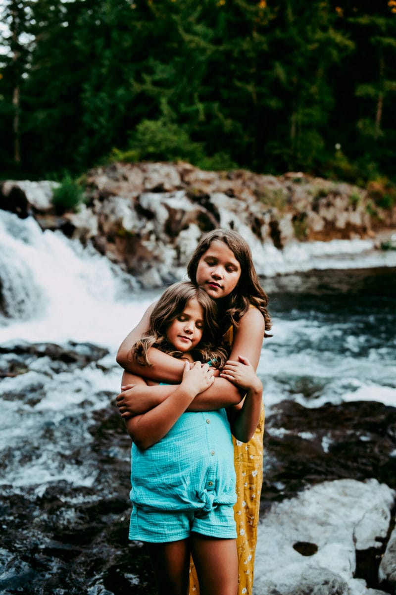 sisters hugging with waterfall in the background
