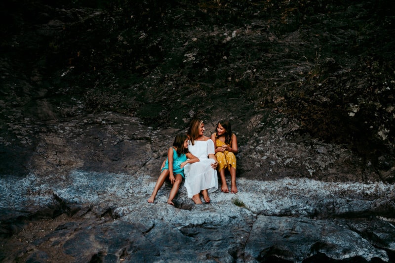 mother and daughters sitting on rocks in washington