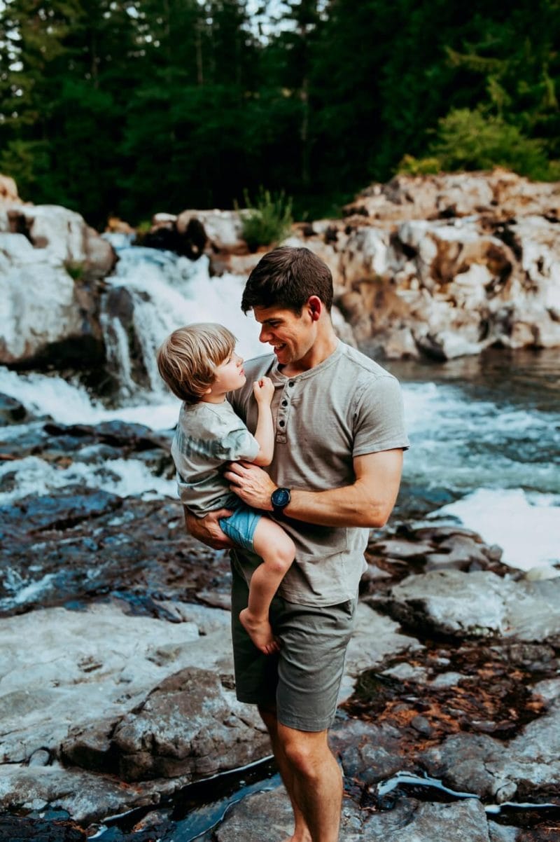 dad-looking-at-child-waterfall-in-the-backgound