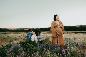 pregnant woman in wildflower field with family in the background