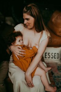 Family Photographer, a mother breastfeeds her baby, she is happy
