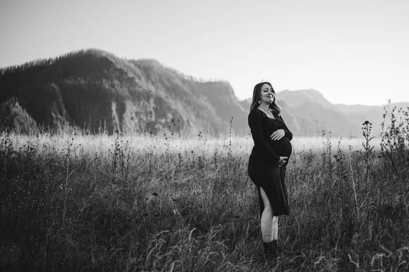 PREGNANT WOMAN DURING MATERNITY SESSION AT COLUMBIA RIVER GORGE WEARING GREEN DRESS