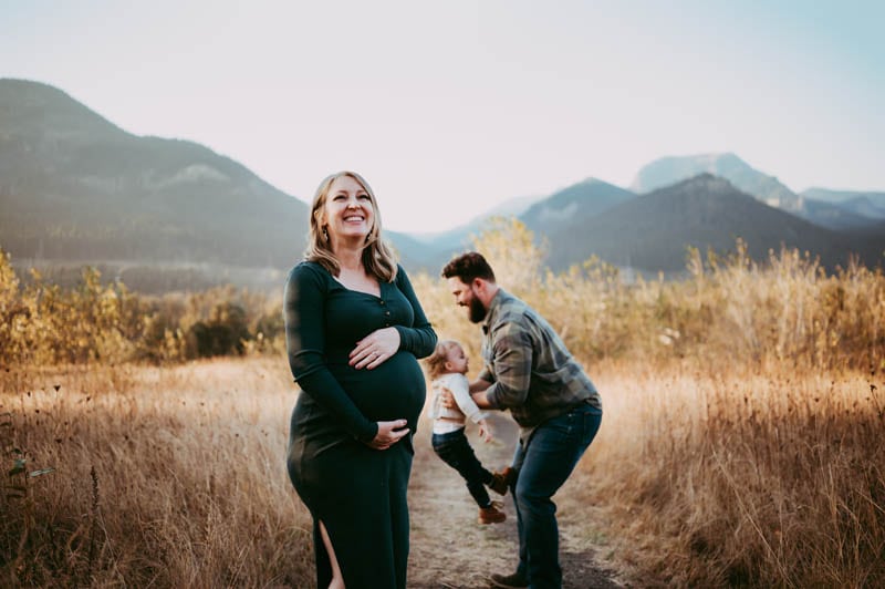 PREGNANT WOMAN DURING MATERNITY SESSION AT COLUMBIA RIVER GORGE WEARING GREEN DRESS