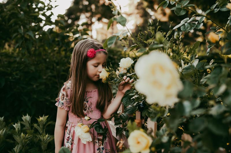 girl smelling flowers at outdoor garden