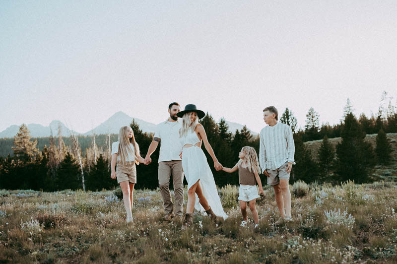 family of 6 walking in a field of flowers during photoshoot for posh baby portland